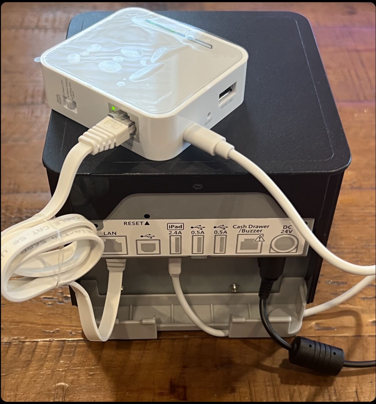 Mini router sitting on top of the printer with ethernet and micro USB cables connected